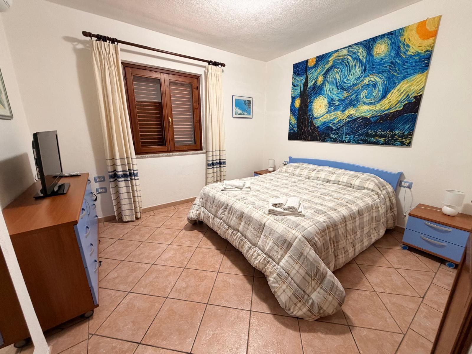 Double bedroom with wall artwork at Casa del Sole — vacation rental in San Teodoro, Sardinia