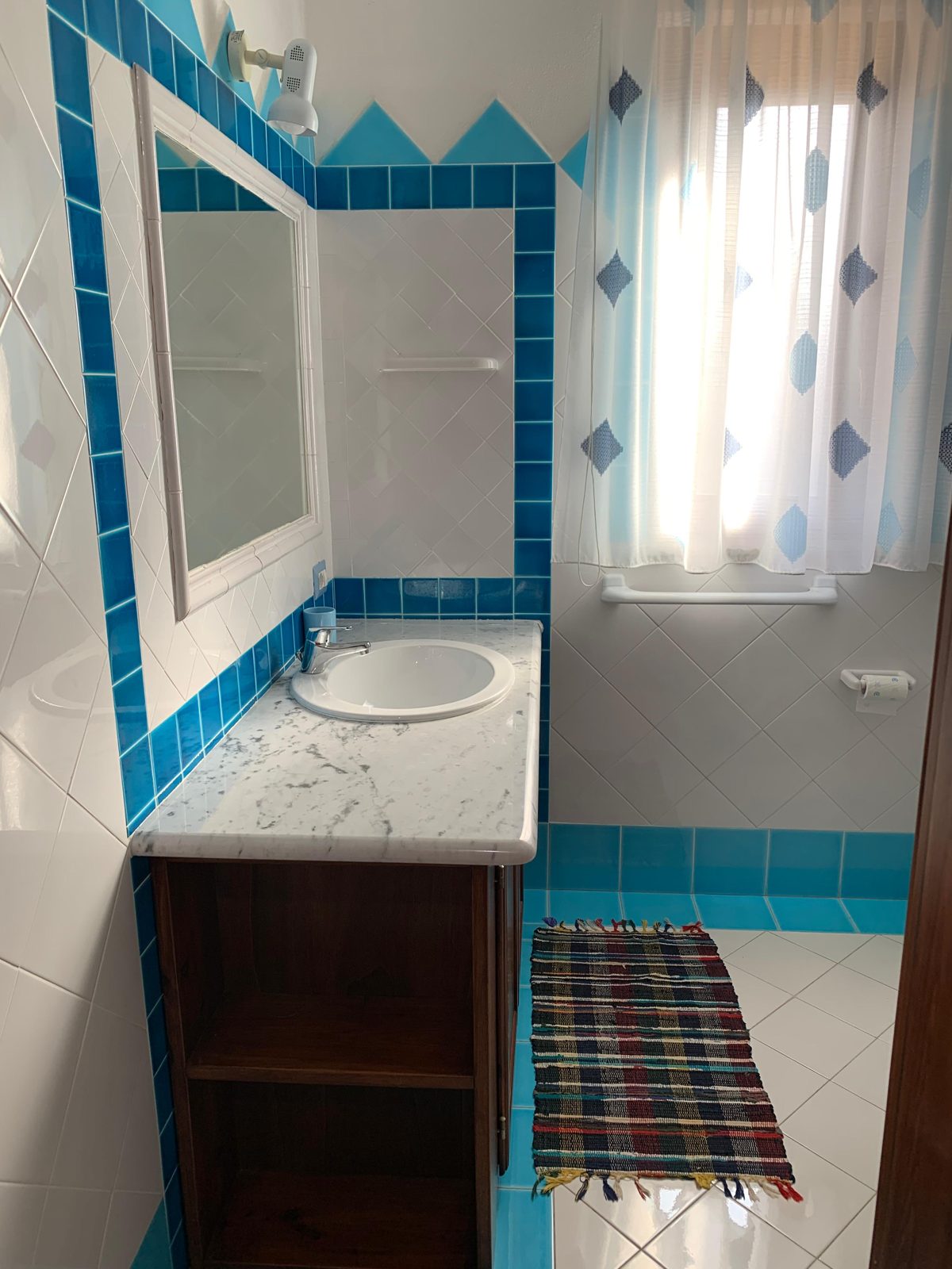Bathroom with turquoise tiles, shower and washbasin at Terrazza sul Mare — vacation rental in San Teodoro, Sardinia